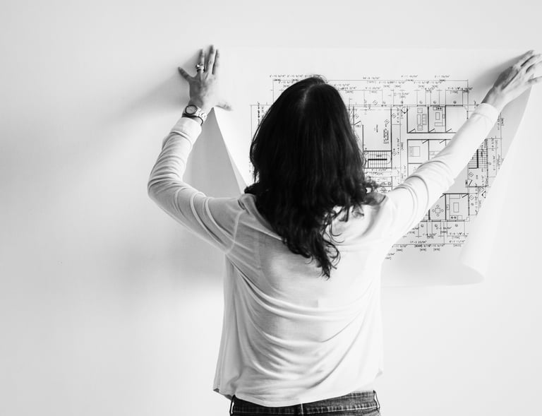 Engenheira fixando uma planta de projeto na parede de um apartamento