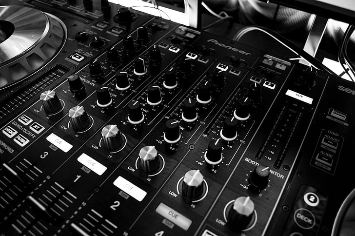 A close-up view of a professional DJ mixer with multiple knobs, faders, and controls.