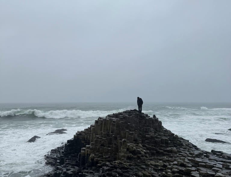 a person standing on a rock formation in the ocean