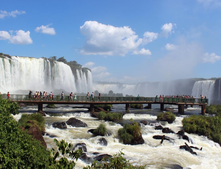 a bridge over a waterfall in the middle of a river