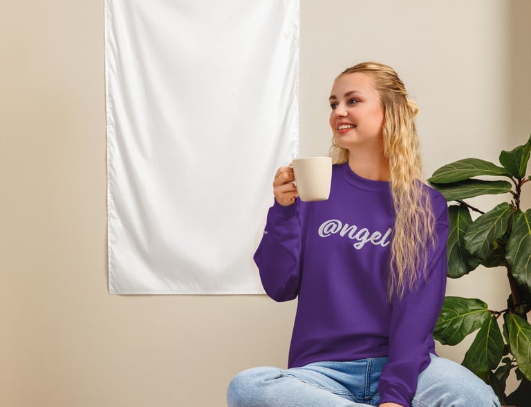 a woman in purple @ngel sweatshirt sitting on a table with a cup of coffee