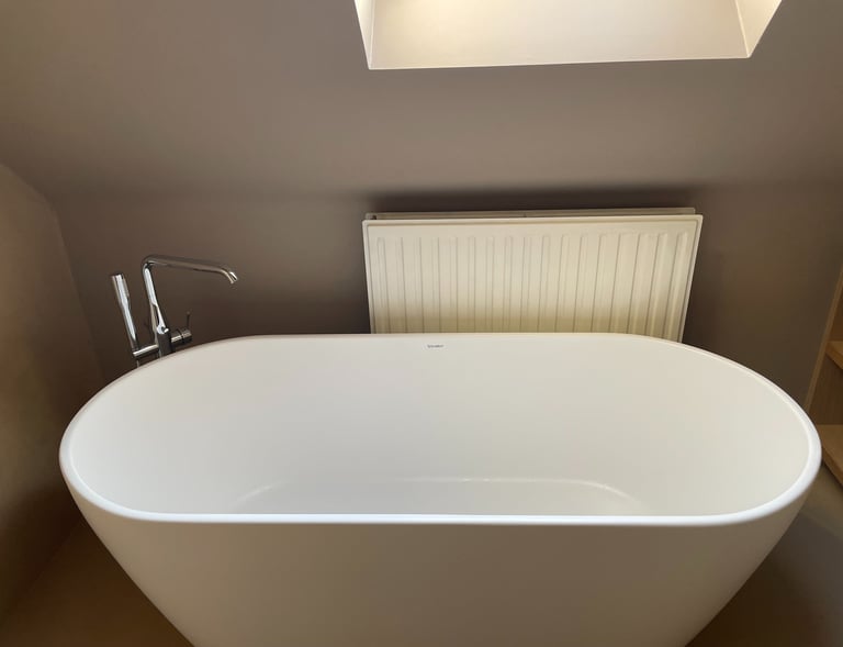 Ligbad met chromen kraan en een radiator in compacte badkamer