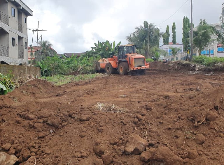 An orange front-end loader leveling soil at a residential construction site for land clearing.