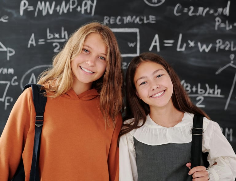 Smiling GCSE Maths students standing in front of their GCSE Maths tutors black board