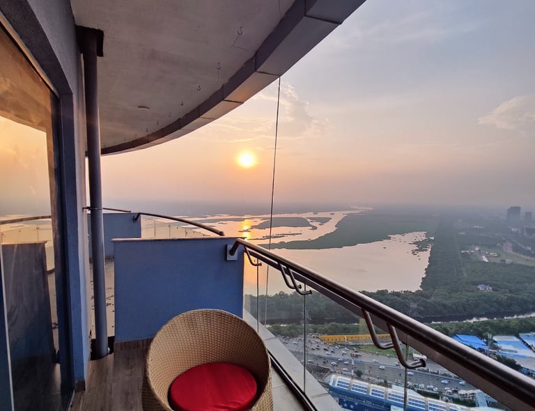 a balcony with a view of the sun setting at Zenith Suites - Noida, Supernova, Supertech