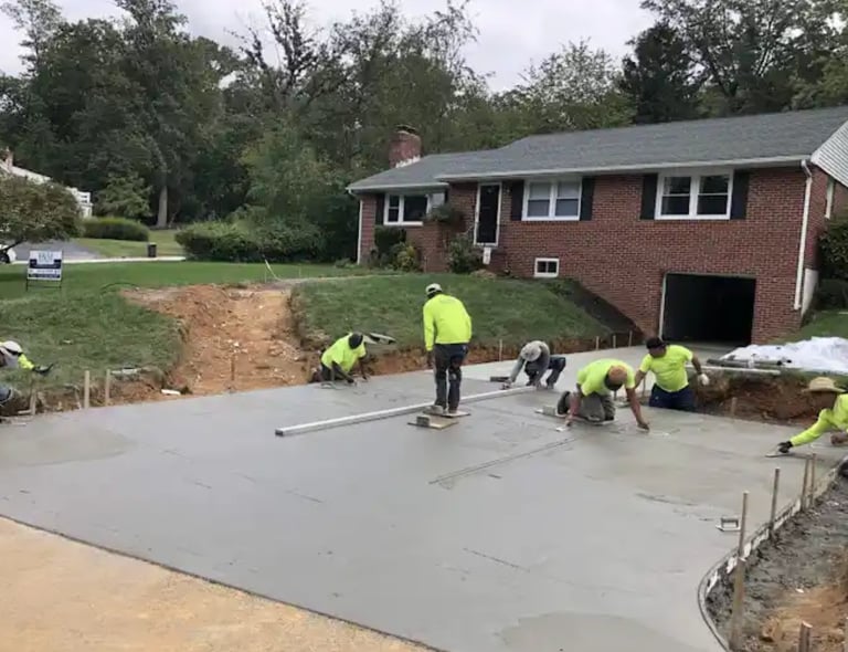 a group of men in yellow jackets and yellow jackets working on a concrete slab