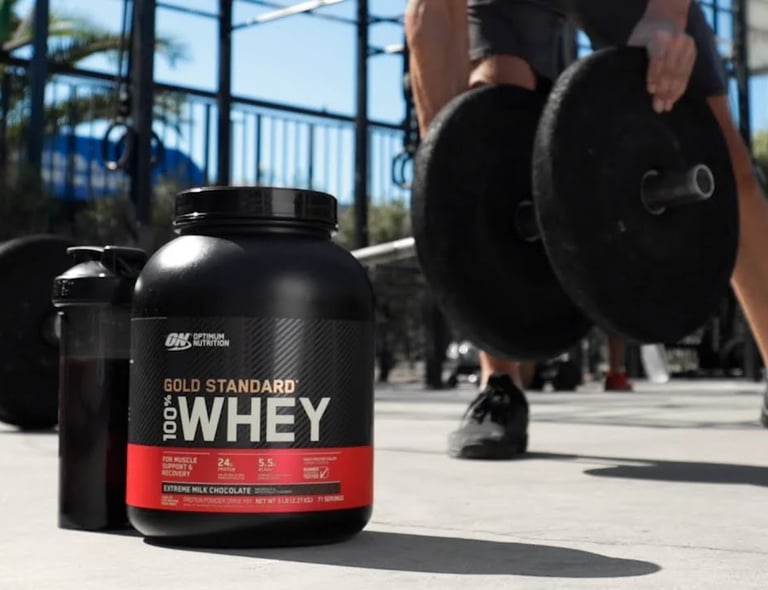 a man is holding a barbell and a bottle of whey