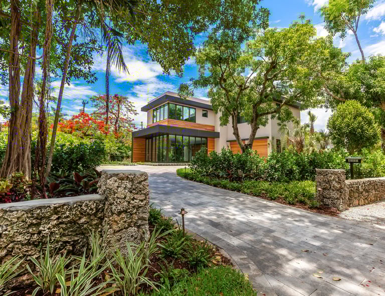 brick driveway leading to a vibrant front yard of a custom built luxury home