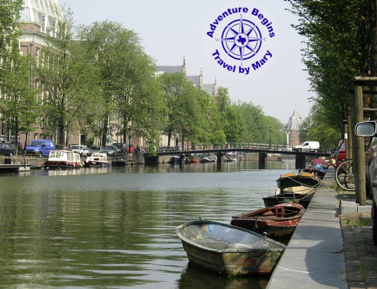 A photo of a Canal in Amsterdam with multiple boats and a bridge...taken by Mary Morong.