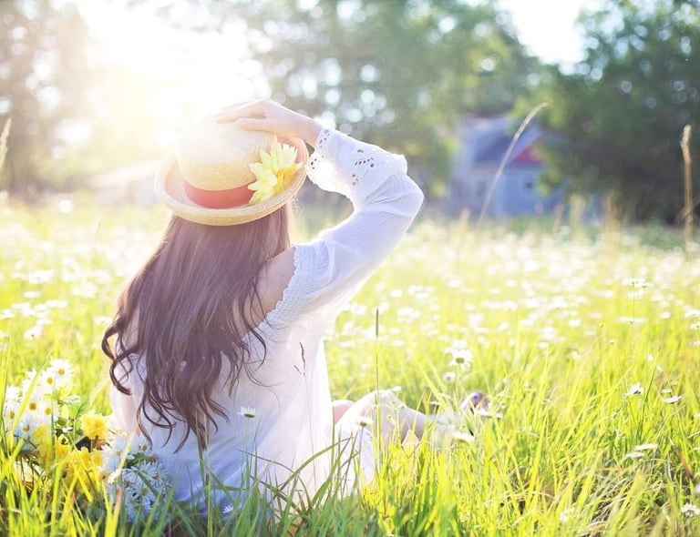 a woman in a hat sitting in a field