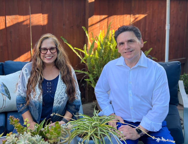a man and woman sitting on a couch in a backyard