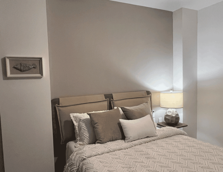 Recámara con cama tapizada, iluminación cálida y paleta de colores neutros en interiorismo acogedor