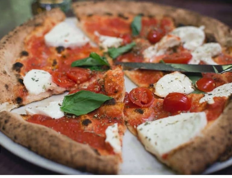 Pizza artisanale généreuse de chez PIZZ’ENTREPOTES servie dans l'ambiance indus du food court.