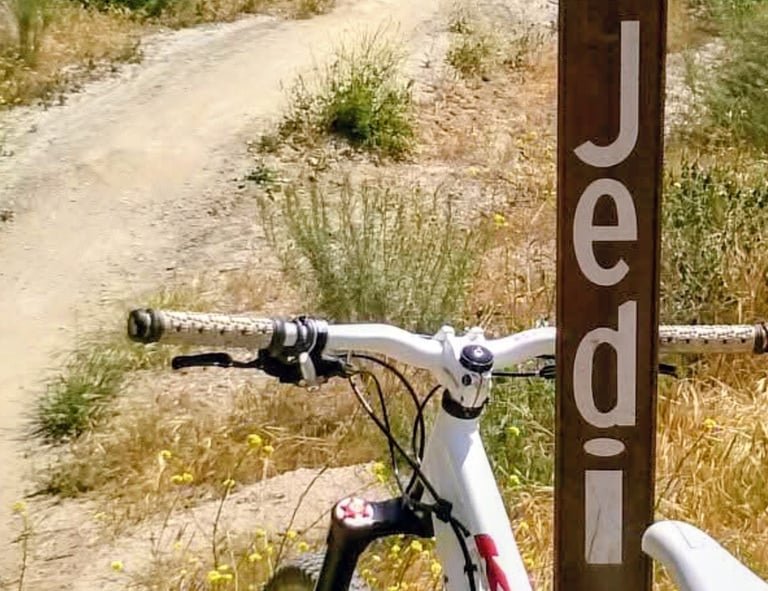  White mountain bike leaning against a blue square trail marker sign on a dirt singletrack trail at 