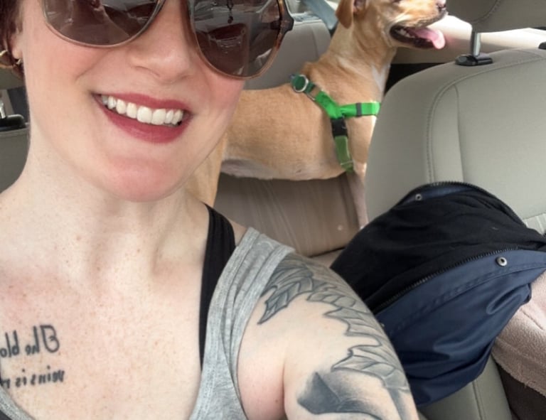 a woman with tattoos on her arm and a dog in the car