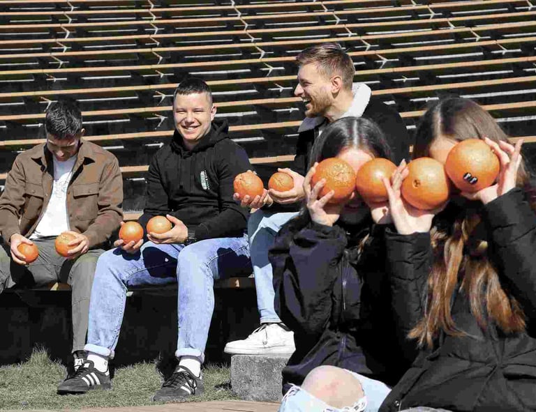 Penki jauni zmones linksmai leidzia laika, zaidzia su apelsinais