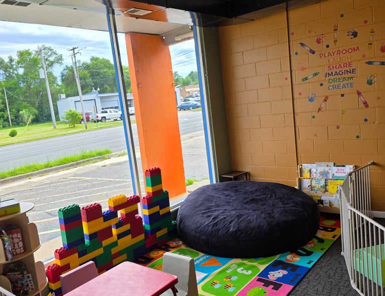 Indoor children's playroom with colorful alphabet mat, giant bean bag, and oversized building blocks.