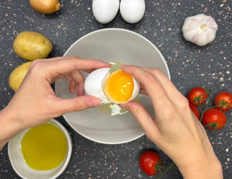 Hands breaking an egg with potatoes, onions and eggs for a Spanish cooking class in Tallinn, Estonia