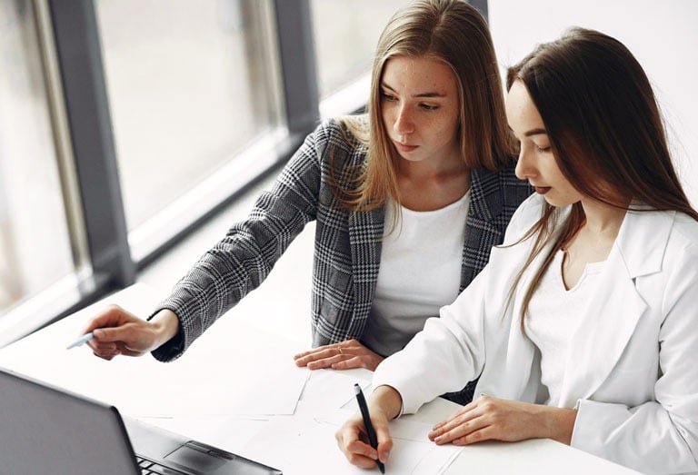 two women sitting at a desk discussing business