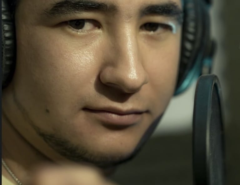 Un cantante masculino con audífonos profesionales grabando frente a un micrófono de estudio.