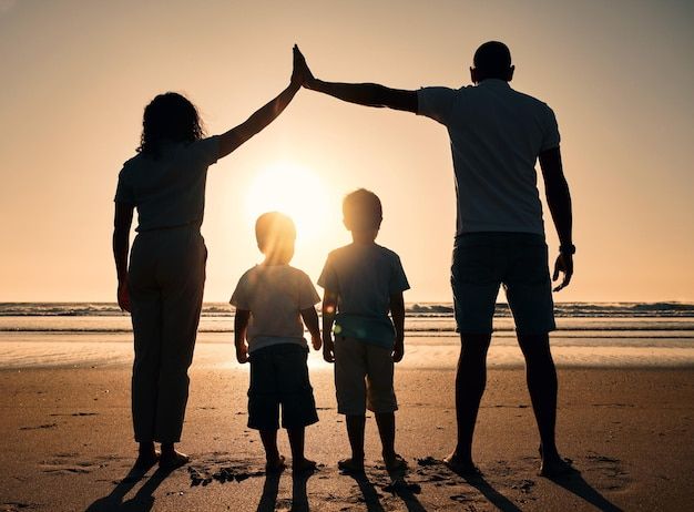 uma família de três pessoas em pé na praia