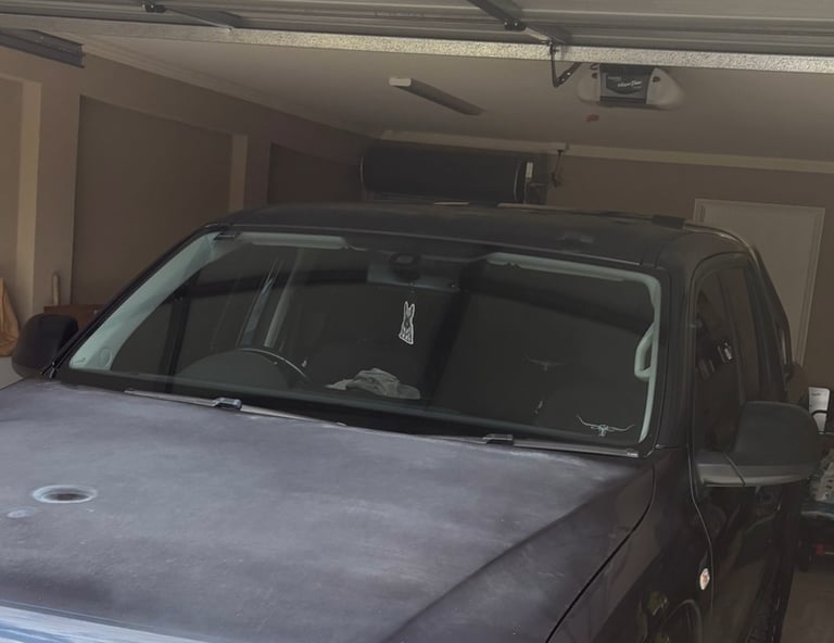 A black ute in a garage showing sun-damaged paint on the hood.