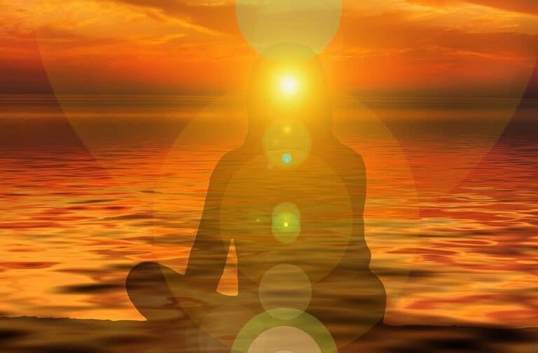 meditierenden Person bei Sonnenuntergang über dem ruhigen Meer mit leuchtenden Chakra-Energiezentren