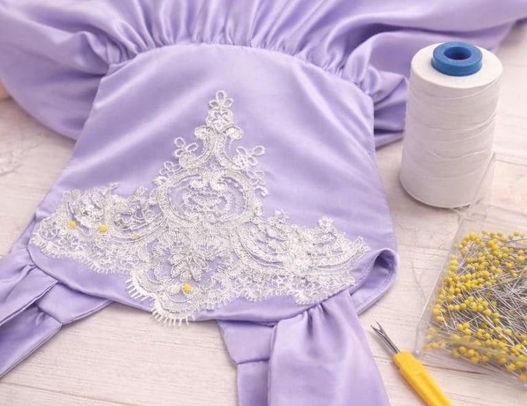 Vestido artesanal de satén morado con bordado de encaje blanco, siendo confeccionado con alfileres
