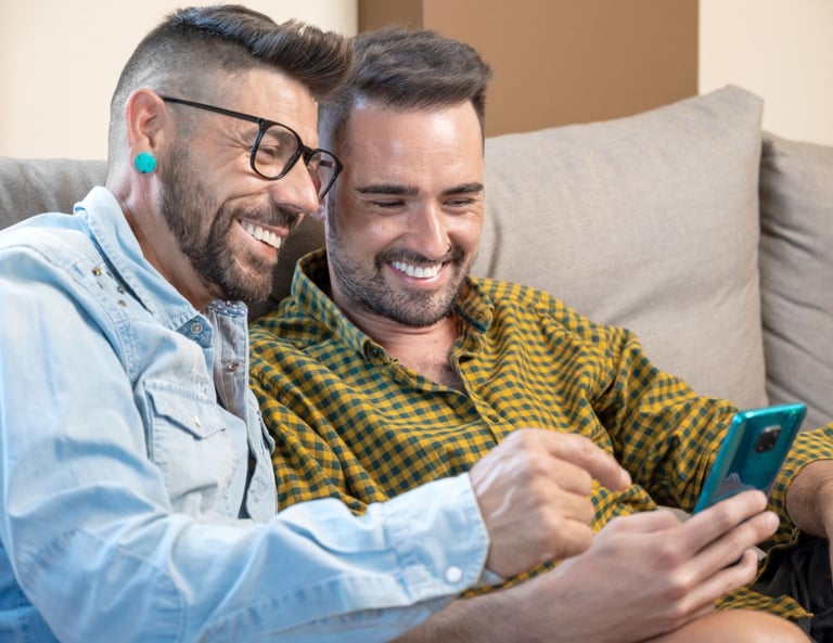 two men sitting on a couch looking at their phones