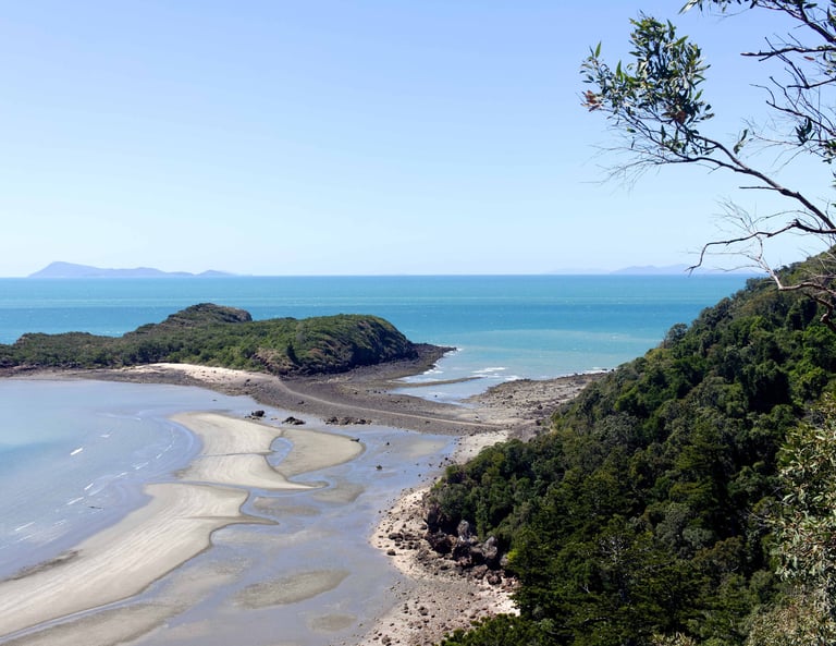Panoramic view of a tropical coastline with sandy beaches, rocky headlands, and lush green forest.