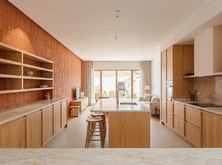 Modern open-plan kitchen with wooden cabinets, marble island, and plaster-finished walls