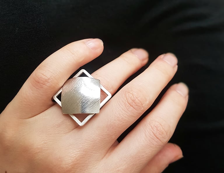 a woman's hand holding a silver ring