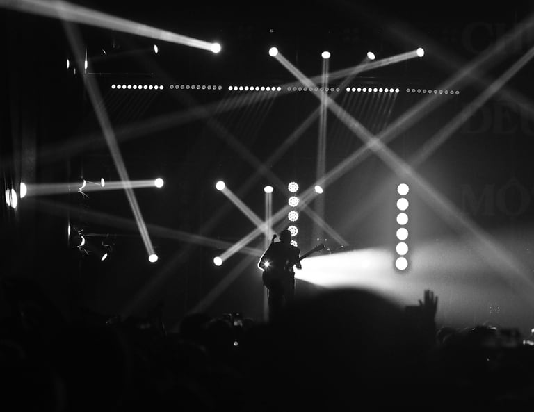 Musician on stage during a live concert with dramatic lighting.