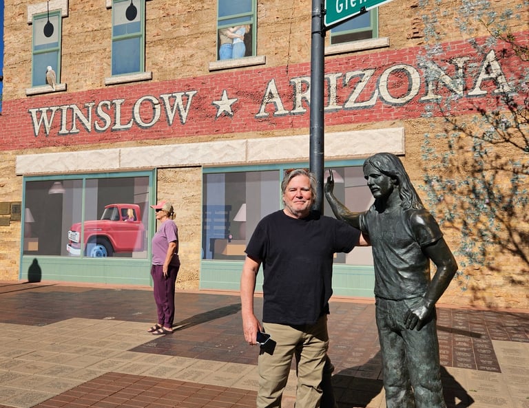 A man poses with the Glenn Frey statue at Standin' on the Corner Park in Winslow, Arizona.