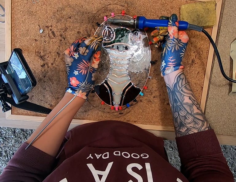a person who is soldering a sun catcher, stainglass