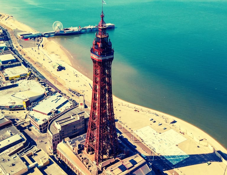 Aerial view of the iconic Blackpool Tower overlooking the sandy golden  beach and the Pier. Sea.