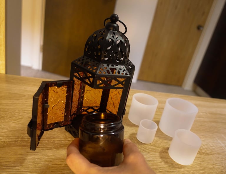 Candle lantern with amber glass panels and silicone molds on a wooden table.