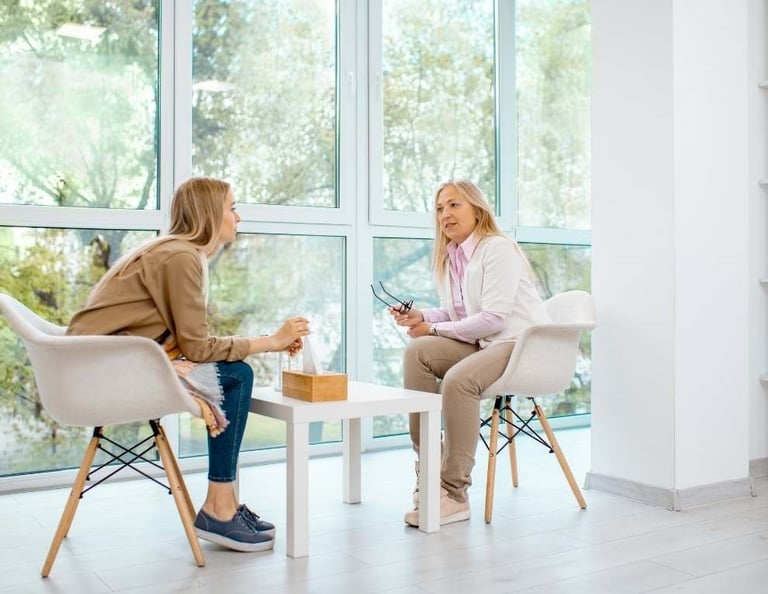 two women sitting at a table with a cup of coffee