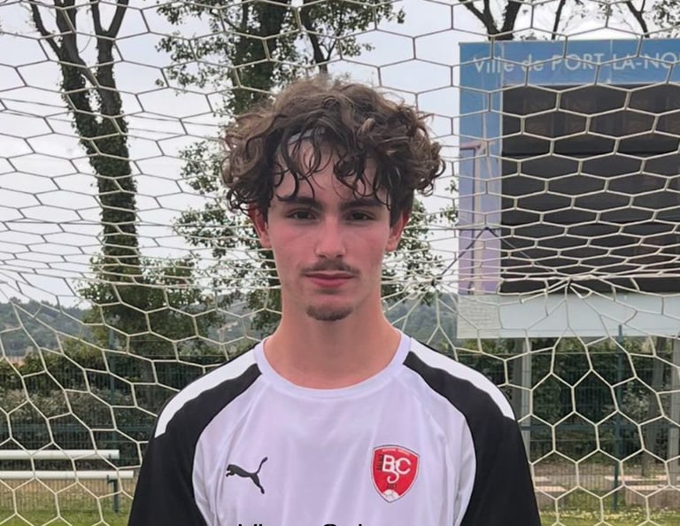 un homme tenant un trophée devant un gardien de but de football