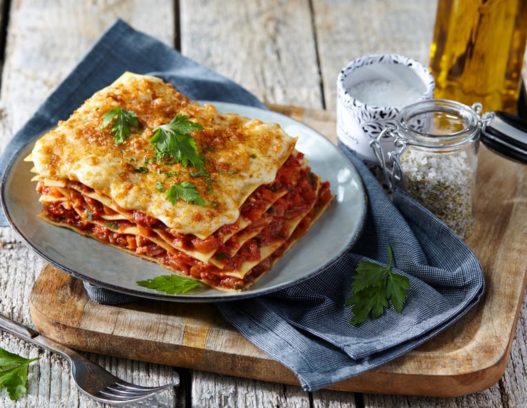 part de lasagne posé sur une planche en bois
