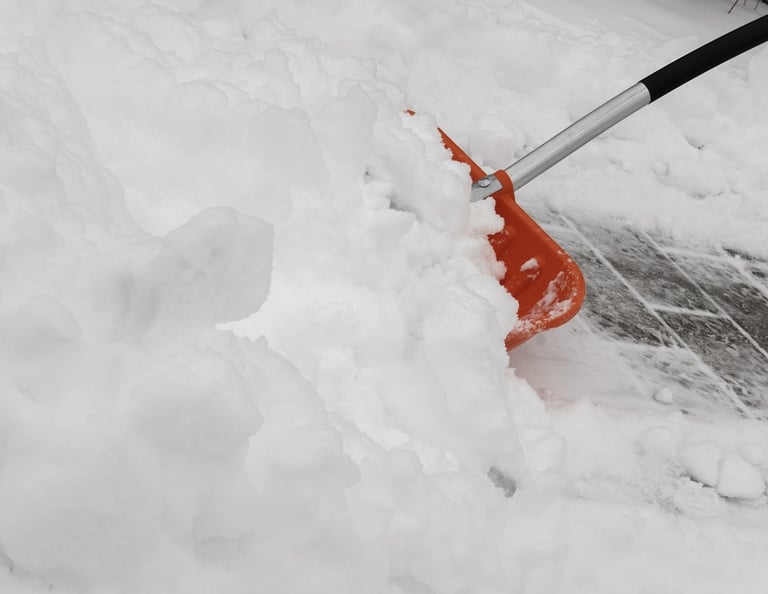 Los Chicos Exterior Solutions team member shoveling snow off a Guelph driveway to keep the property 