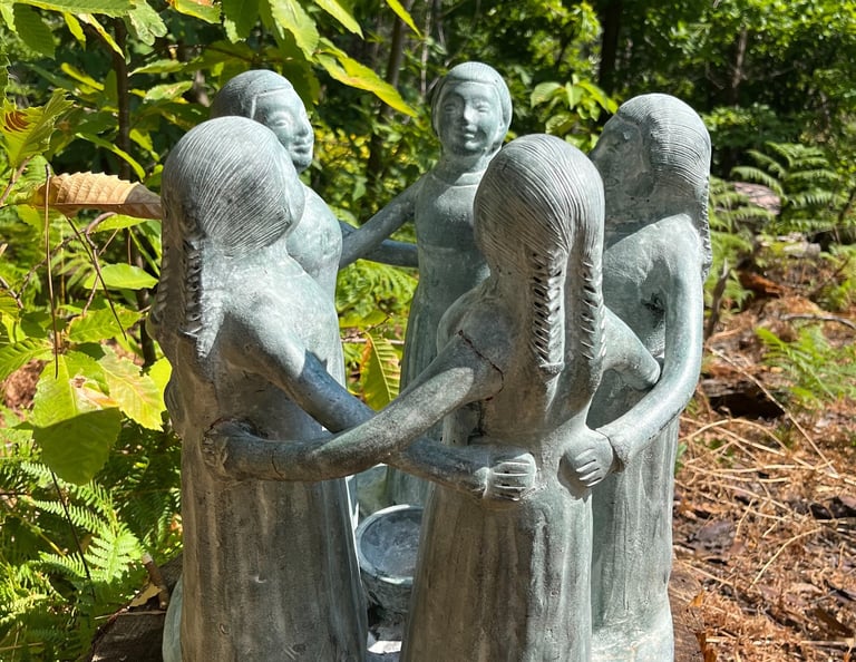 a statue of a group of women around a tree stump