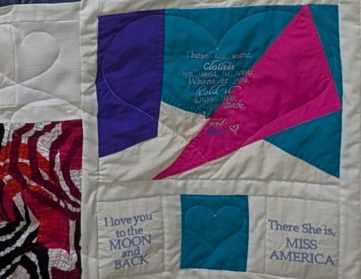 Memory quilt pieced from fabric cut from clothing with an embroidered message on the bottom right