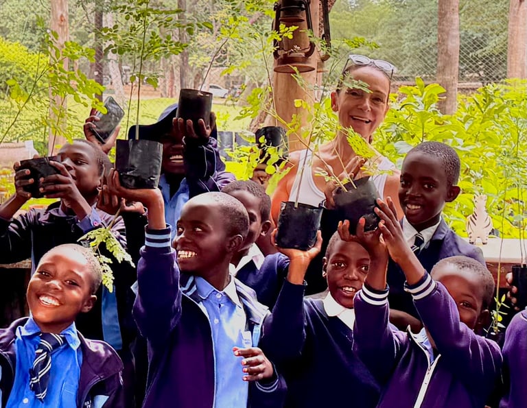 Smiling school children surrounding teacher and all holding up small trees