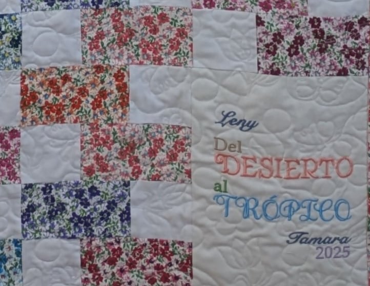 Floral block quilt with meandering butterfly quilting and a personal message embroidered in corner