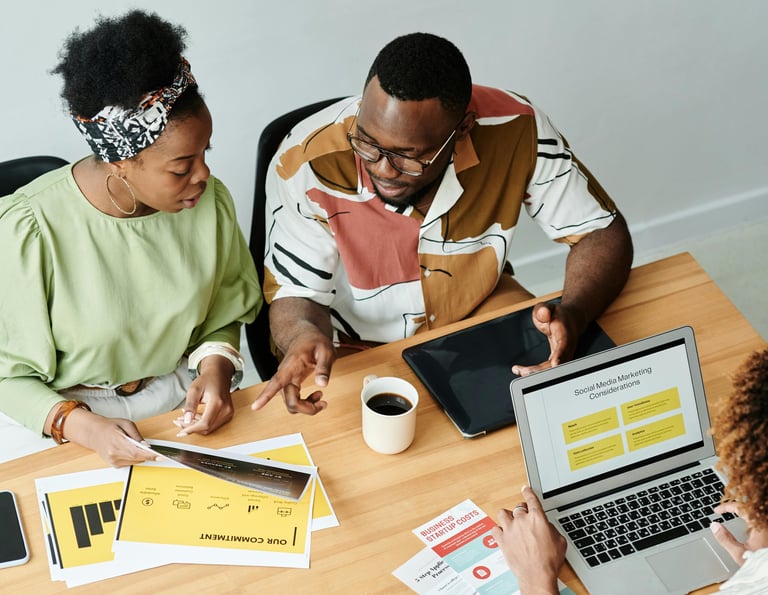 "Estrategistas de mercado de arte em reunião analisando documentos de planejamento e métricas de soc