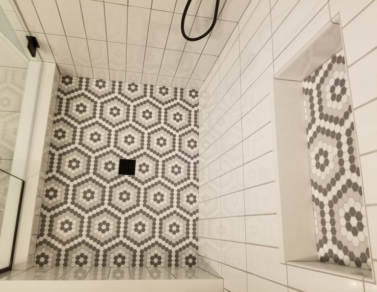Modern walk-in shower featuring gray and white geometric hexagon floor tile and white vertical subway wall tile.