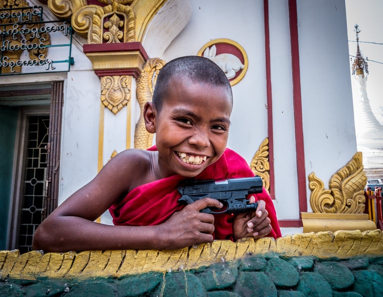 A young novice monk enjoys playing with a toy gun.
