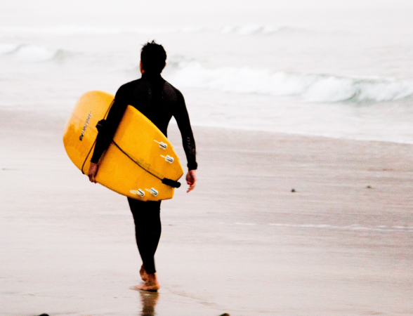 a man in a wetsuit is holding a surfboard
