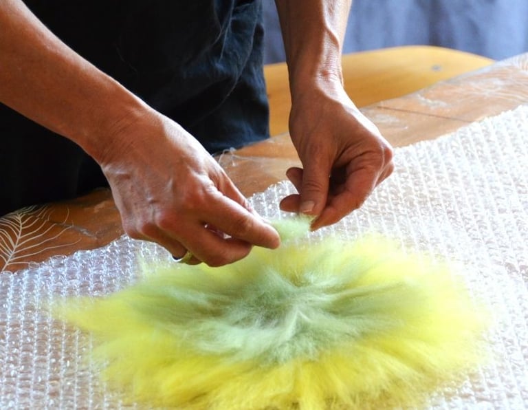 Gros plan sur mes mains disposant la laine pour être feutrée